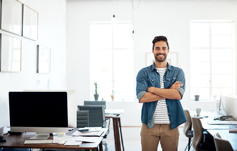 Project Manager Junior šťastne pózuje medzi stolmi v kancelárii