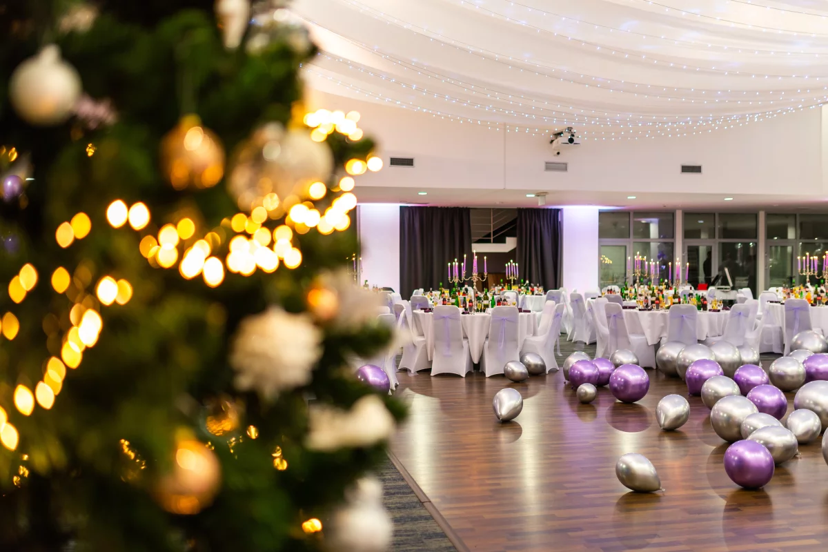 Weihnachtsfeier msg life 2022 – msg life Slovakia farebné balóny na podlahe sály, nazdobené stoly a vianočný stromček v popredí